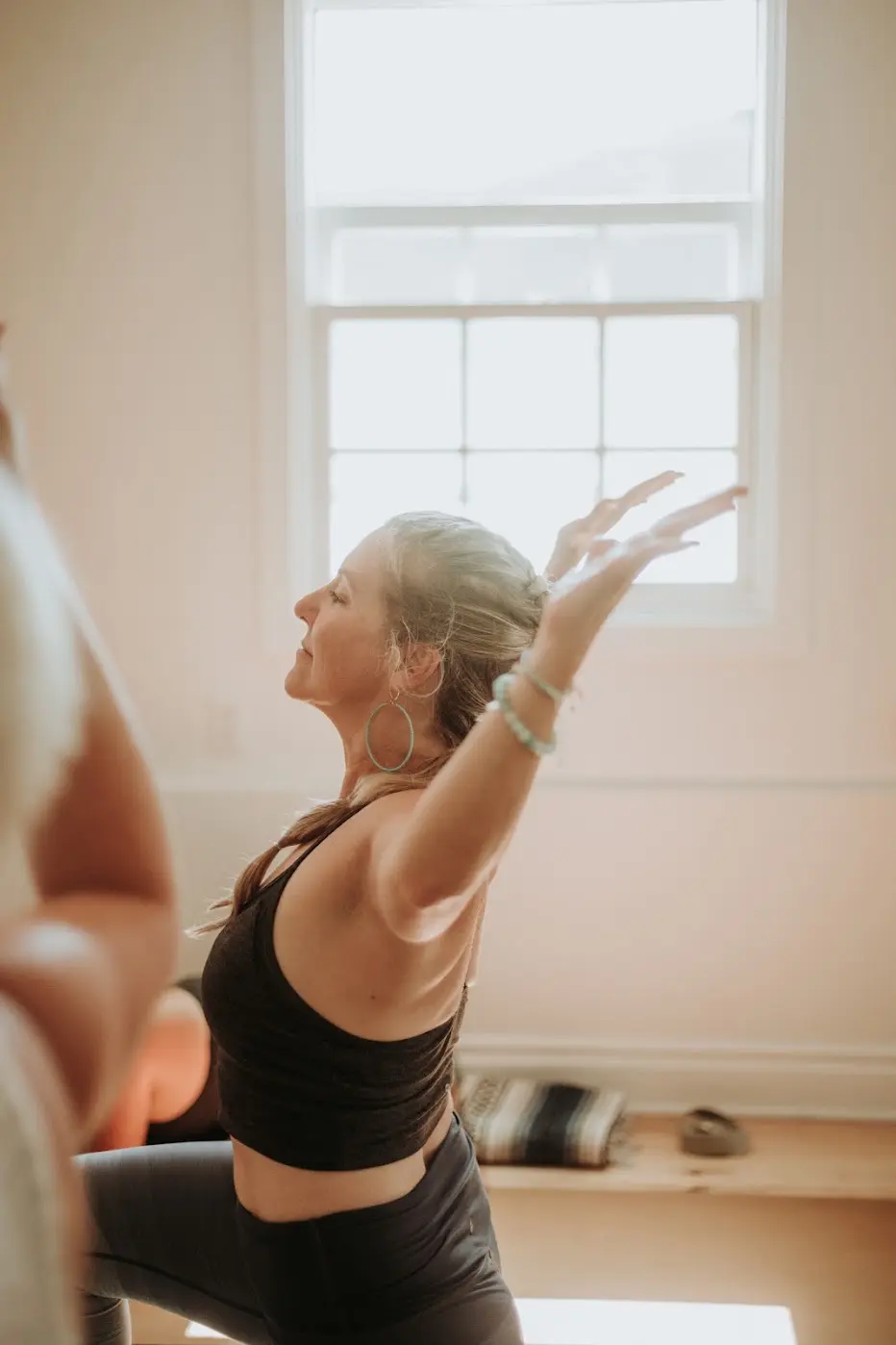 Yoga instructor in a warrior pose with arm raised
